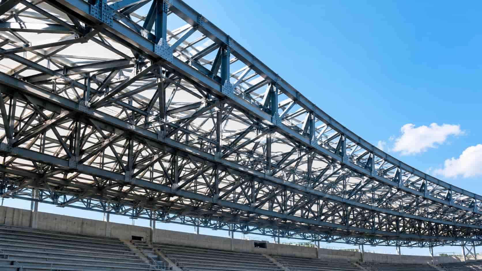 tadium steel truss roof close-up, curved beams, bold geometry, bright sky, tiered seating