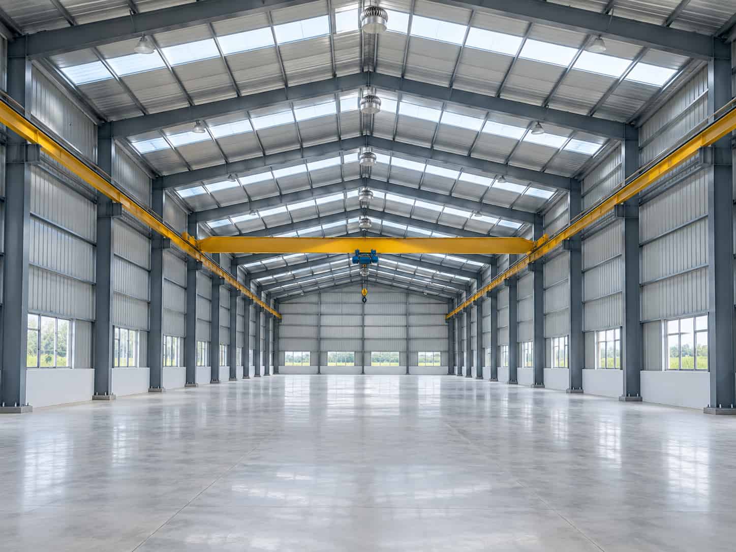 Interior of a finished steel factory shed with a column-free floor, overhead crane and natural daylight