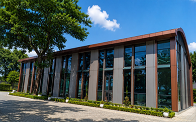 Curved steel framed conference building with full-height glazing and timber-toned columns